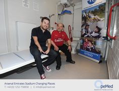 two men sitting on top of a bench in a room next to a sign that says emirates