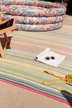 a pair of sunglasses sitting on top of a multicolored rug next to a chair