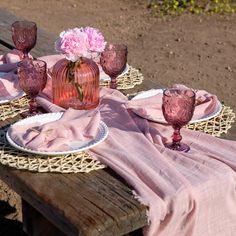 the table is set with pink glassware and napkins