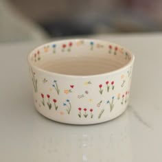 a white bowl with flowers painted on the outside and inside, sitting on a table