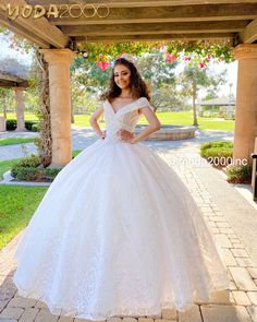 a woman in a white wedding dress standing on a brick walkway with her hands on her hips