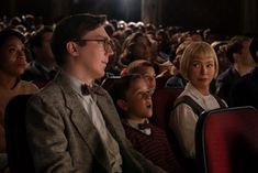 a group of people sitting next to each other in front of a crowd at a movie theater