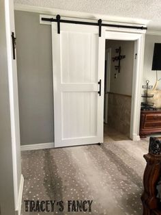 an empty room with a white door and black hardware on the sliding barn doors that are open