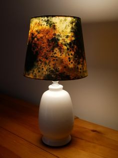 a lamp that is sitting on top of a wooden table in front of a wall