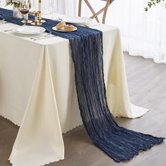 the table is set with white plates and silverware, along with an elegant blue runner