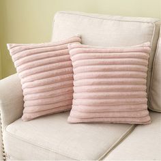 two pink pillows sitting on top of a white couch