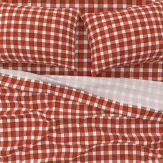 an orange and white checkered comforter set with two pillow cases on top of it