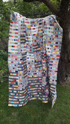 a quilt hanging from a tree in the grass