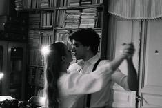 a man standing next to a woman in front of a bookshelf