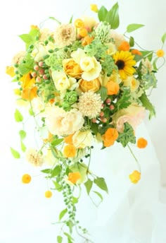 a bridal bouquet with sunflowers, roses and greenery is hanging from the ceiling