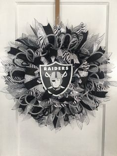 a black and white wreath with the oakland football team on it is hanging in front of a door