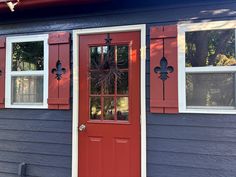 a red front door and window on a blue house with white trim, in the daytime