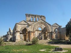 an old stone church in the middle of a grassy area with steps leading up to it