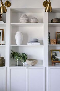 some white shelves with vases and pictures on them