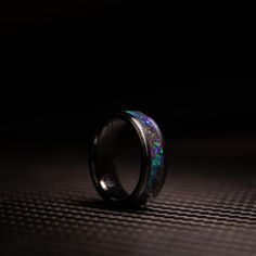 a black ring with green and blue fire opal inlays on the inside