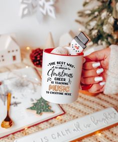 a person holding a coffee mug in front of a christmas tree with snowmen on it