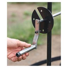 a hand is holding onto the handle of a metal gate with a circular object attached to it