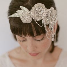 a woman wearing a bridal headpiece with pearls and leaves on it's side