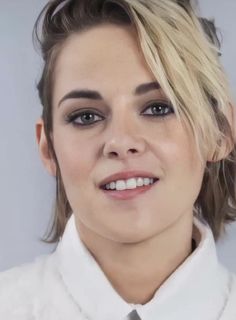 a woman with blonde hair wearing a white shirt and gray tie smiling at the camera