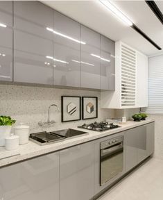 a kitchen with stainless steel appliances and white counter tops, along with potted plants