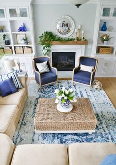 a living room with two chairs and a coffee table in front of a fire place