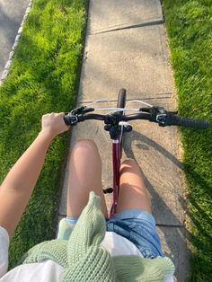 a person riding a bike down a sidewalk next to a grass covered field and walkway