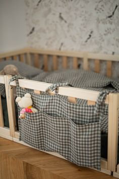 a baby crib with two stuffed animals in it's pocket and some fabric hanging from the rails