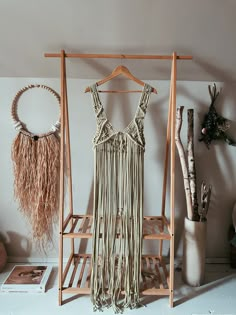 a dress hanging on a clothes rack next to some plants and other things in a room