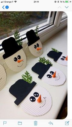 paper snowmen with hats and carrots in front of a window