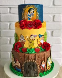 a three tiered cake decorated with snow white and the seven dwarfs