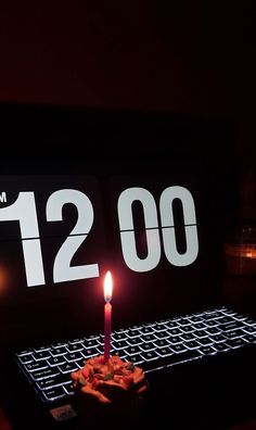 a lit candle sitting on top of a keyboard in front of a sign that reads 120