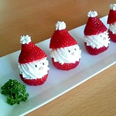 four red and white strawberries with santa hats on them are sitting on a plate