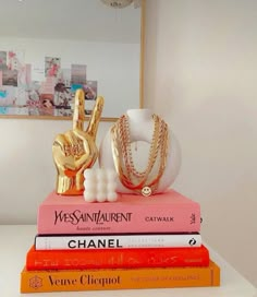 three books stacked on top of each other in front of a mirror and chandelier