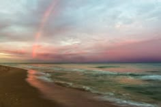 a rainbow appears over the ocean at sunset