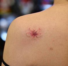 the back of a woman's shoulder with a small flower on her left side