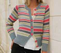 a woman leaning against a wall wearing a striped cardigan