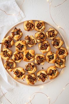 a white plate topped with mini pastries covered in nuts and raisins on top of a table