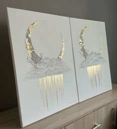 two paintings with gold foil on them sitting on top of a wooden dresser next to a window