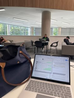 an open laptop computer sitting on top of a table next to a handbag and purse