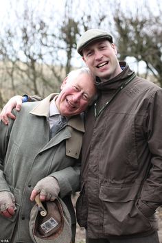 two men standing next to each other with one holding a hat and the other smiling