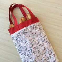 a red and white bag with two croissants in it on a table