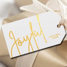 a gift wrapped in gold and white paper with the word joyful written on it