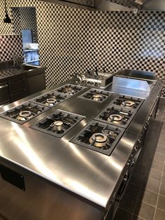 an industrial kitchen with stainless steel appliances and checkered backsplash