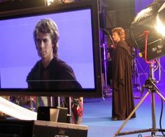 a man is standing in front of a television set with lights on and behind him