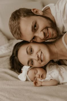 a man and woman laying on top of a bed holding a baby