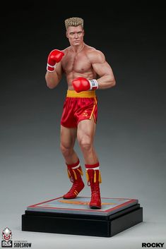 a statue of a man wearing boxing gear and holding a red glove in his right hand