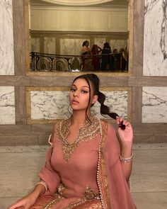 Brown girl wearing a pink desi outfit fit on grande stairs