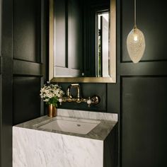 a white sink sitting under a bathroom mirror next to a gold framed mirror and wooden cabinets