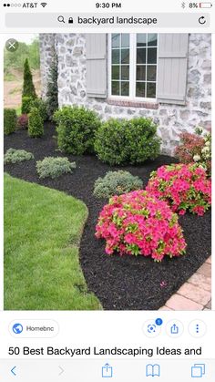 a stone house with flowers in the front yard