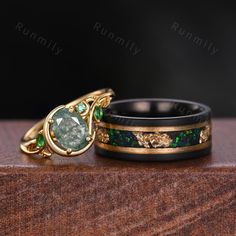 two wedding bands with green stones and gold rings on top of each other, sitting next to each other